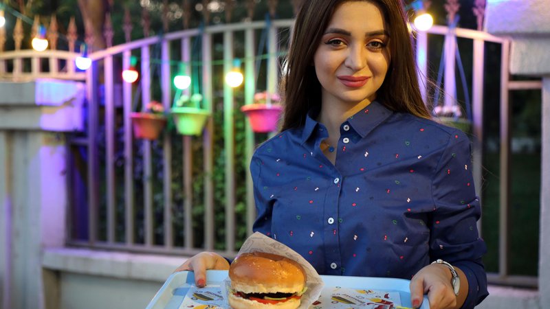 Fotografija: V svoji prikolici v Erbilu Zilan Servud ne pripravlja kakšnih lokalnih specialitet, ampak »globalno« hitro prehrano – hamburgerje, ocvrt krompir in čebulne obročke. FOTO: AFP