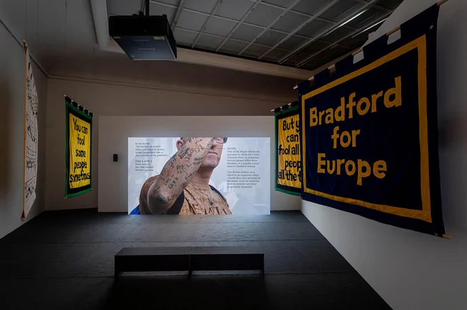 Jeremy Deller se poglobi v subjekte z antropološko natančnostjo, pozorno zazna vsako njihovo gesto, besedo in simbole, zapisane na transparentih, oblekah ali vtetovirane v kožo. Foto Mathias Voelzke