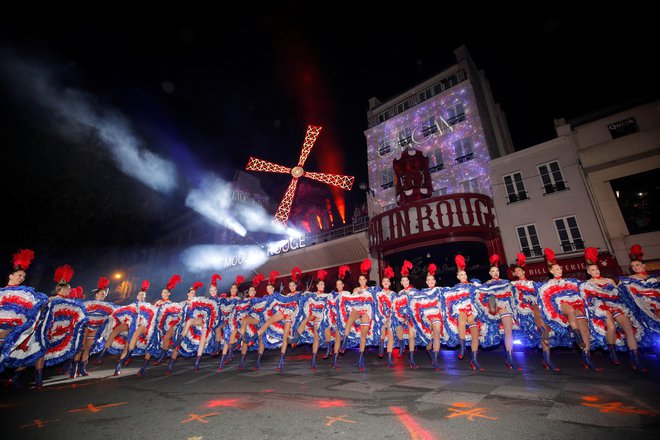 Da bi 130. obletnico Moulin Rougea praznovali pompozno, kot je treba, so v nedeljo kar na ulici pripravili minirevijo. V njej je sodelovalo 60 plesalk v kostumih francoske modre, bele in rdeče barve. Foto Reuters