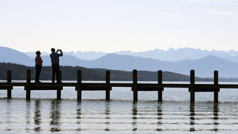 Fotografija: People take a photo of the Alps from a footbridge of the lake Starnberg in front of the Alp mountains near the small Bavarian village of Starnberg, southern Germany, during nice autumn weather with temperatures by 15 degrees on October 17, 2019. (Photo by Christof STACHE / AFP)