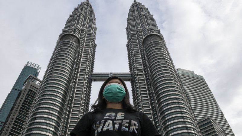 Fotografija: Celia Cheng pred eno najvišjih stavb na svetu, Petronas Twin Towers v prestolnici Malezije Kuala Lumpurju z masko na obrazu, nošenje katerih je v Hongkongu od oktobra prepovedano. FOTO: AFP