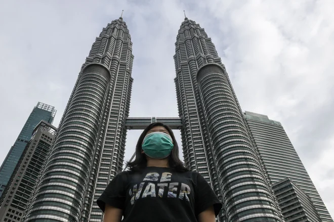 Celia Cheng pred eno najvišjih stavb na svetu, Petronas Twin Towers v prestolnici Malezije Kuala Lumpurju z masko na obrazu, nošenje katerih je v Hongkongu od oktobra prepovedano. FOTO: AFP