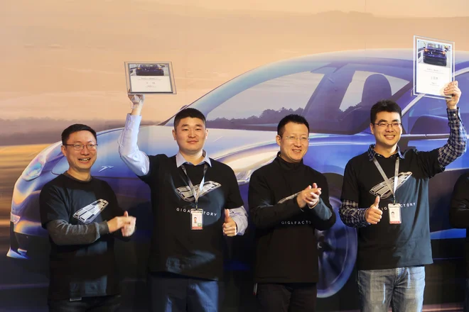Vodja kitajske tovarne Tesla Zhu Xiaotong in drugi zaposleni na slovesni predaji prvih avtomobilov. FOTO: Sun Yilei /Reuters