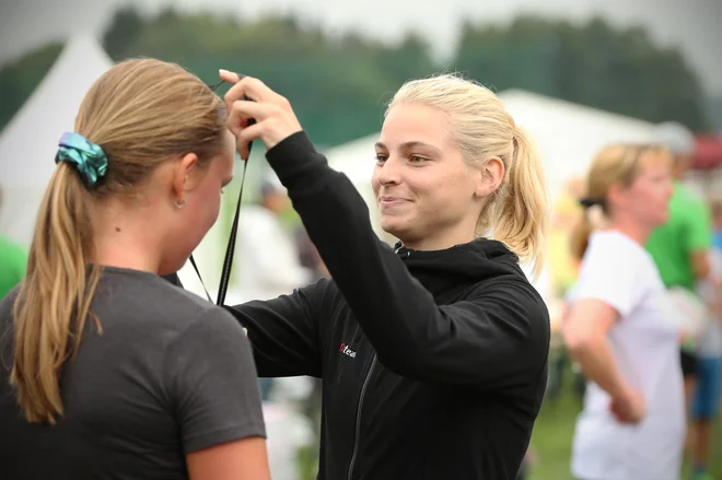 Smučarska skakalka Špela Rogelj deli medalje. Tek Triglav za dober namen, rekreacijo, zabavo in druženje. Brdo pri Kranju, Slovenija 7.septembra 2019. [Rogelj Špela,otroci,medalje,čestitke,prireditve,dogodki,zdravje,rekreacija,gibanje,tekači,druženje,špor