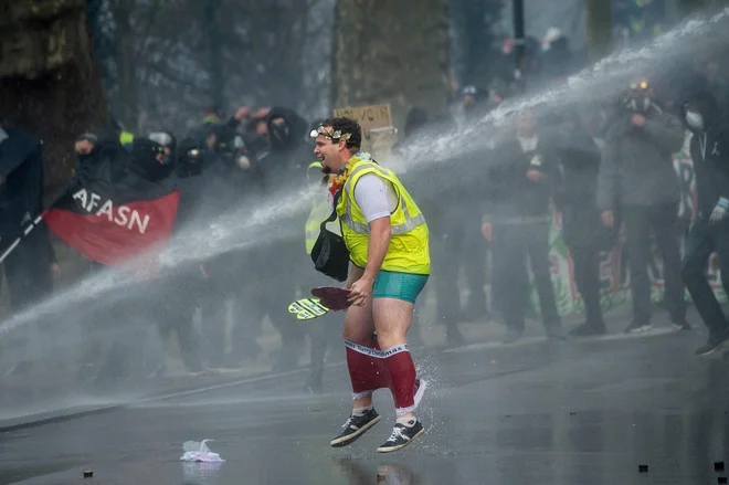 Člana francoskega protivladnega gibanja Rumeni jopiči je v francoskem mestu Nantes namočil policijski vodni top, med stavko zaradi vladne pokojninske reforme. FOTO: Loic Venance/Afp<br />
