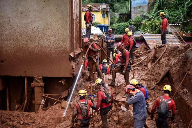 Blato morajo odstranjevati z novo vodo, da lahko pridejo do morebitnih preživelih v stavbah. FOTO: Afp