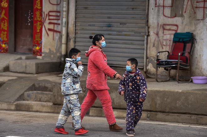 Prizor v predmestju Wuhana je enak prizorom po vsej širši regiji: ljudje nosijo zaščitne maske. FOTO: AFP