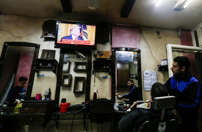 Palestinci v Gazi gledajo televizijski posnetek tiskovne konference v Beli hiši. FOTO: Mahmud Hams/AFP