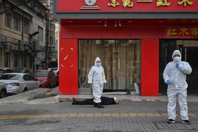 Starejši moški z obrazno masko se je zrušil in umrl na ulici v bližini bolnišnice v Wuhanu. Svetovna zdravstvena organizacija je razglasila globalno nevarnost zaradi novega koronavirusa, saj je Kitajska poročala že o 213 smrtnih žrtvah in več kot 10.000 okuženih. FOTO: Hector Retamal/Afp<br />
