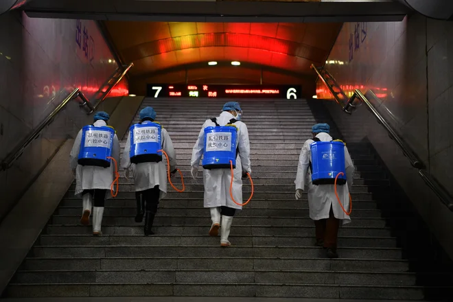 Zdravstveni delavci razkužujejo železniško postajo v mestu Kunming. FOTO: Reuters