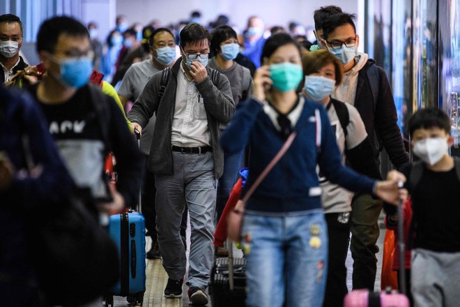 Potniki ob prihodu iz Shenzhena v Hongkong nosijo zaščitne maske. FOTO: AFP