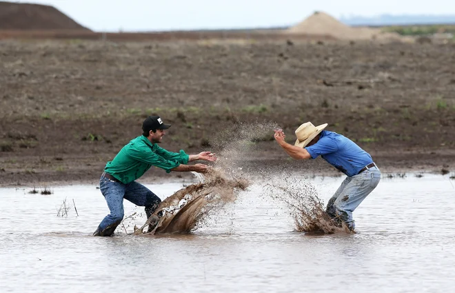 Soseda s kmetij v Liverpool Plains v Novem južnem Walesu James Purshouse (levo) in Jock Tudgey se veselita obilnega dežja, ki je končal triletno sušo in omejil nekaj mesecev trajajoče požare. FOTO: Stringer/Reuters