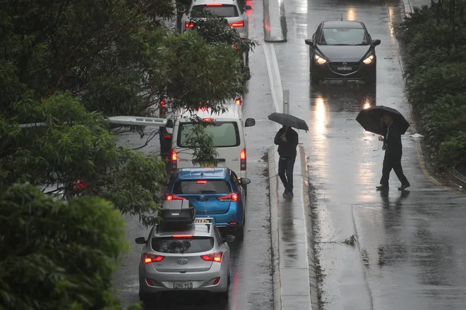 Pešci v Sydneyju v borbi z močnim vetrom. FOTO: Loren Elliott/Reuters