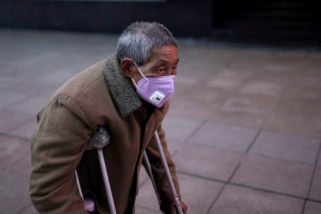 V najmanj dveh kitajskih pokrajinah in v številnih mestih si morajo ljudje, ko stopijo iz hiše, na obraz obvezno namestiti kirurško masko. FOTO: Aly Song/Reuters