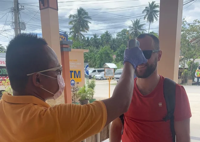 Številni turistični delavci nosijo zaščitne maske in merijo temperaturo potnikom, ki se vkrcavajo na letala in ladje. FOTO: Gašper Mlakar