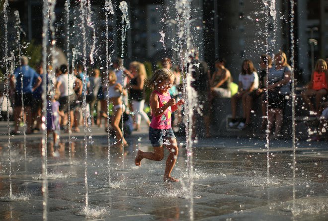 Ljudje se hladijo in osvežujejo v diamičnem vodnjaku na Mestnem trgu. FOTO: Jure Eržen/delo