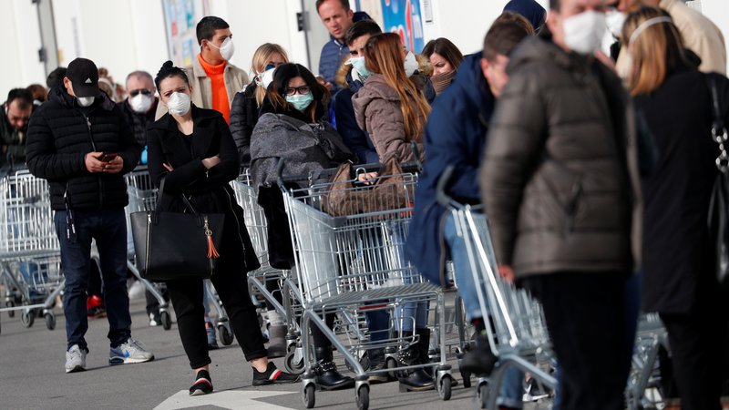 Fotografija: V mesto Casalpusterlengo v severni Italiji, ki je zaradi izbruha virusa zaprto v karenteno, ljudje v vrstah stojijo pred trgovinami z živili. FOTO: Guglielmo Mangiapane/Reuters