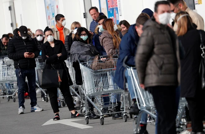 V mesto Casalpusterlengo v severni Italiji, ki je zaradi izbruha virusa zaprto v karenteno, ljudje v vrstah stojijo pred trgovinami z živili. FOTO: Guglielmo Mangiapane/Reuters