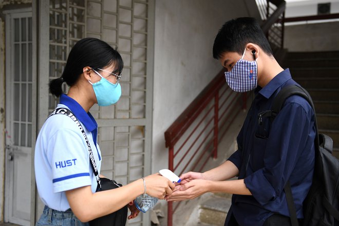 Po šesttedenskih izrednih počiticah so študnetom ob vrnitvi v šolske klopi najprej razkužili roke. FOTO: Nhac Nguyen/AFP