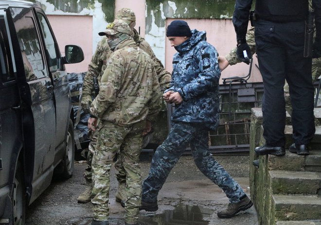 Član ruske Zvezne varnostne službe (FSB) vodi ukrajinskega mornarja na zaslišanje. FOTO: Pavel Rebrov/Reuters