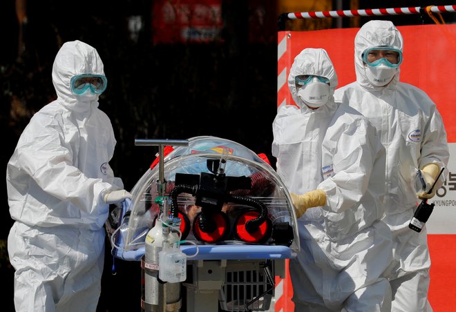Zdravstveni delavci ob pacientu, okuženem s koronavirusom, ​v Daegu (Južna Koreja). FOTO: Kim Kyung-hoon/Reuters
