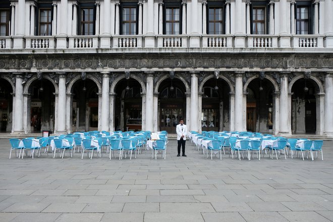 Natakar med prazniki mizami pred restavracijo na Trgu sv. Marka v Benetkah. FOTO: Manuel Silvestri/Reuters