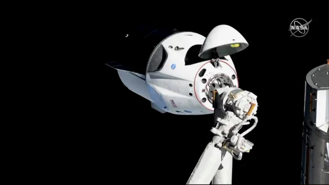 Dragon za človeško posadko ob približevanju postaji lani marca. FOTO: Nasa/Reuters