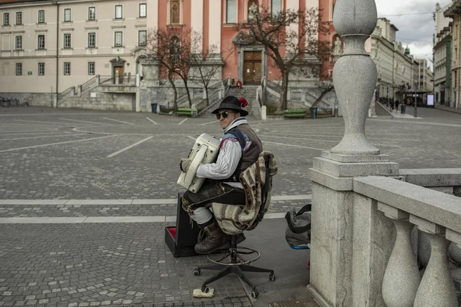 Harmonikaša na Prešernovem trgu ni pregnala niti epidemija niti prazne ulice. FOTO: Voranc Vogel