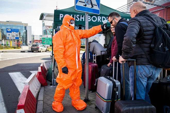 Strožji režim je na notranjih in zunanjih schengenskih mejah. Na fotografiji poljski zdravstveni delavec meri telesno temperaturo potnikom na meji z Nemčijo. FOTO: Odd Andersen/AFP