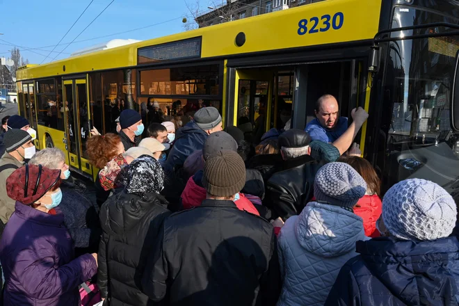 Desetine ljudi čaka na avtobusnem postajališču v Kijevu, potem ko je Ukrajina omejila število potnikov, ki se vozijo na avtobusu, na maksimalno 10 naenkrat, kot ukrep proti širjenju koronavirusa. FOTO: Genya Savilov/Afp<br />
