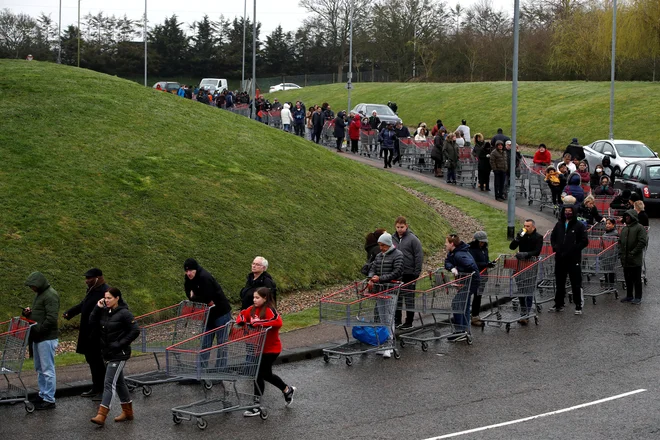 Ljudje čakajo v dolgi vrsti pred trgovino Costco v Watfordu, saj se širjenje koronavirusa v Veliki Britaniji nadaljuje. FOTO: Paul Childs/Reuters