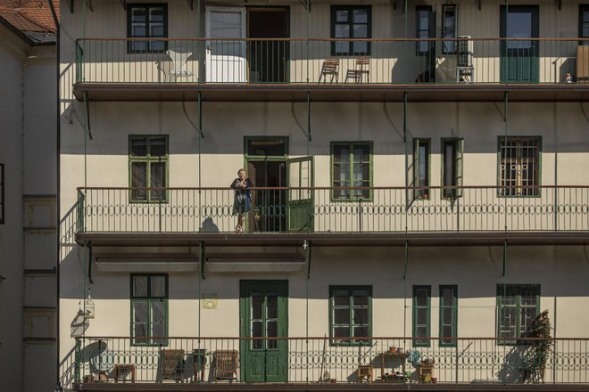 Ljudje v času izolacije gledajo skozi okna. FOTO: Voranc Vogel
