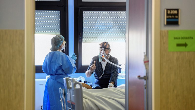 Fotografija: Zdravstvena delavka oskrbuje pacienta z boleznijo covid-19 v bolnišnici Oglio Po v Cremoni. Foto: REUTERS/Flavio Lo Scalzo