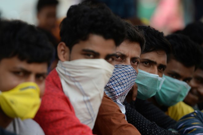 Indijski delavci z improviziranimi zaščitnimi maskami ob uvedbi policijske ure v Chennaiju. FOTO: Arun Sankar/Afp