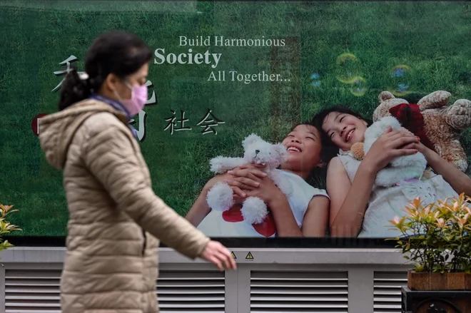 A woman wearing a face mask walks on a street in Wuhan, on April 2, 2020. - Wuhan, the central Chinese city where the coronavirus first emerged last year, partly reopened on March 28 after more than two months of near total isolation for its population of