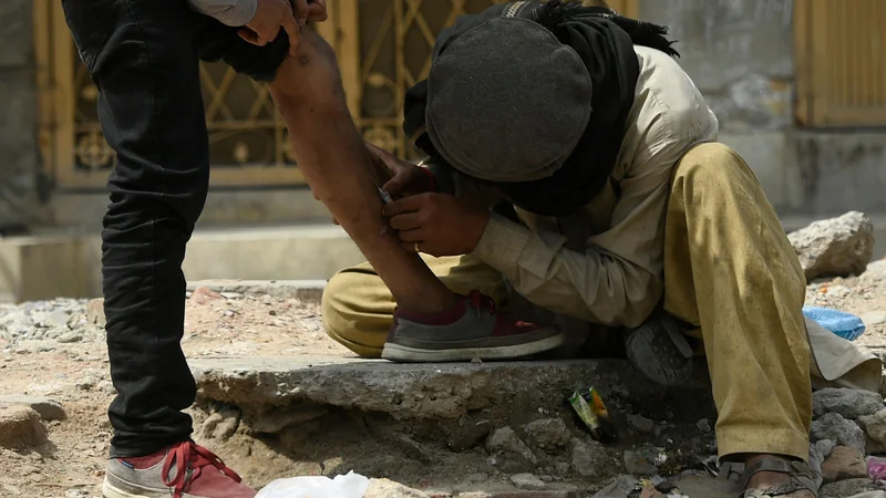 Fotografija: Na ulici v pakistanskem mestu Rawalpindi heroinska odvisnika en drugem vbrizgavata heroin. FOTO: Aamir Qureshi/Afp