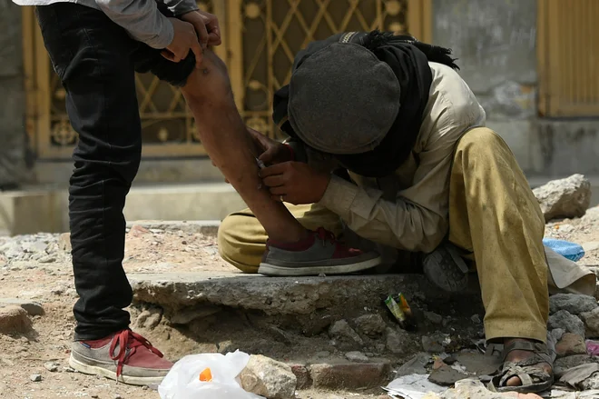 Na ulici v pakistanskem mestu&nbsp;Rawalpindi heroinska odvisnika en drugem vbrizgavata heroin. FOTO: Aamir Qureshi/Afp