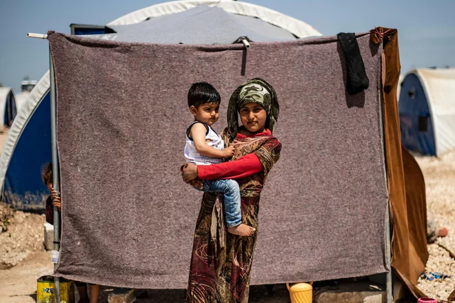 Portret razseljene sirske deklice iz Ras al Aina, obmejnega mesta pod nadzorom Turčije, z dojenčkom v rokah v kampu Washukanni v sirski provinci Hasakeh. FOTO: Delil Souleiman/Afp