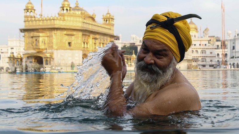 Fotografija: Indijski Sikhi med festivalom Baisakhi molijo pred Zlatim templjem v Amritsarju med karanteno. FOTO: Narinder Nanu/AFP
