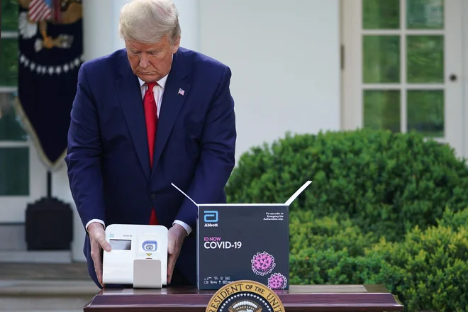 Ameriški predsednik Donald Trump predstavlja enega od Abbottovih testov, ki prinašajo veliko lažje ugotavljanje coronavirusa in protiteles. FOTO: Mandel Ngan/AFP