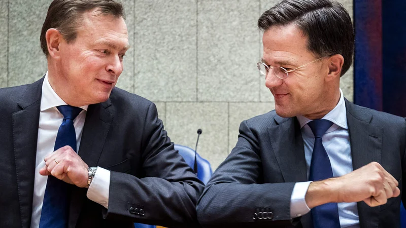 Fotografija: Nizozemski premier Mark Rutte (desno), nizozemski minister za zdravstveno oskrbo Bruno Bruins in njun pozdrav s komolci med sejo spodnjega doma nizozemskega parlamenta. Foto: Remko De Waal/Afp