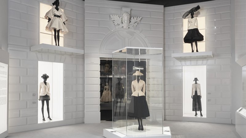 Fotografija: Modni oblikovalec Christian Dior je ženskam po vojnem pomanjkanju z novim videzom, ki ga simbolizira bel oprijet suknjič s širokim plisiranim črnim krilom, rokavicami in zašiljeni salonarji s tanko peto, povrnil feminilnost. Foto Arhiv Muzeja V & A