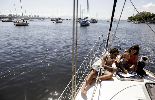 Argentinski par Constanza Coll in Juan Manuel Dordal se igrata s sinom Ulisesom na svoji jadrnici v zalivu Guanabara v Riu de Janeiru. FOTO: Ricardo Morales/Reuters