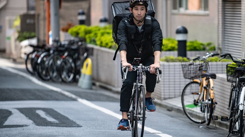 Fotografija: Dostava hrane na kolesu v katerega od bolj hribovitih delov neskončnega Tokia je lahko tudi dober trening. FOTO: AFP
 