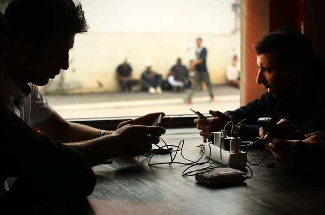 Begunci in migranti polnijo svoje pametne telefone in druge elektronske naprave, v enemu od mestnih lokalov. FOTO: Jure Eržen