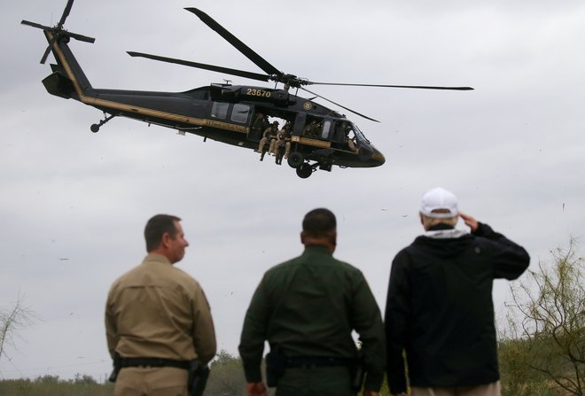 Trump salutira helikopterju ameriške službe za mejni nadzor med obiskom meje z Mehiko. FOTO: Leah Millis/Reuters