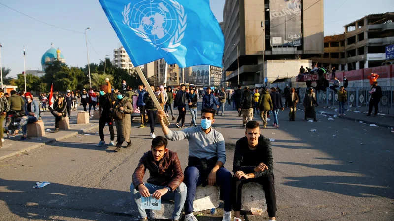 Fotografija: Udeleženec protestov v Iraku z zastavo Združenih narodov. FOTO: Thaier Al-sudani/Reuters