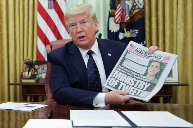 Ameriški predsednik Donald Trump je pred podpisom izvršilnega ukaza razkazoval naslovnico časopisa New York Post.&nbsp;FOTO: Jonathan Ernst/Reuters