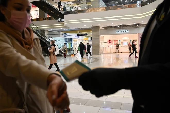 Varnostniki pred trgovskimi centri v Kijevu brezstično preverjajo temperaturo ljudi, ki želijo vstopiti. FOTO: Genya Savilov/Afp
