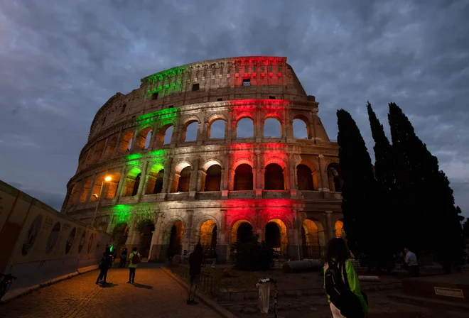 Sinoči so pročelje Koloseja v Rimu osvetlili z barvami italijanske zastave v čast žrtvam koronavirusne bolezni z vsega sveta. FOTO: Tiziana Fabi/AFP
